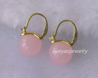 Puede incluir: Un par de pendientes de aro de oro con acentos de piedras redondas rosas. Los pendientes son simples y elegantes.
