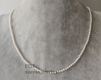 May include: A white pearl necklace on a gray fabric background. The necklace is made of small, round pearls and is about 18 inches long. The text "ETSY: xueyaojewelry" is visible in the lower right corner of the image.