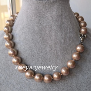 May include: A necklace with large, round, champagne-coloured beads. The beads are strung together and fastened with a silver-toned clasp. The text "xueyaojewelry" is visible on the necklace.