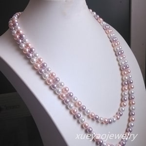 Könnte beinhalten: Eine mehrreihige Perlenkette mit rosa, weißen und lavendelfarbenen Perlen. Die Kette wird auf einer weißen Puppe präsentiert.