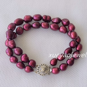 May include: A double-strand bracelet featuring deep burgundy-colored freshwater pearls. The pearls are irregularly shaped and strung together. The bracelet is secured with a silver-colored clasp. The text "xueyaojewelry" is visible.