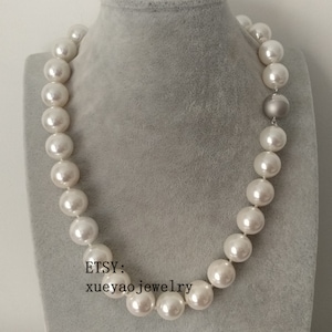 Peut inclure: Un collier de perles blanches avec un fermoir argenté. Les perles sont grandes et rondes, et le collier mesure environ 45 cm de long.