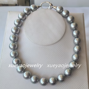 May include: A silver pearl necklace with a silver clasp. The necklace is made of large, round pearls.