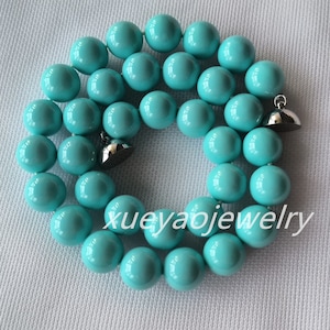 May include: A turquoise blue beaded necklace with silver clasps. The necklace is made of round beads and is approximately 18 inches long.
