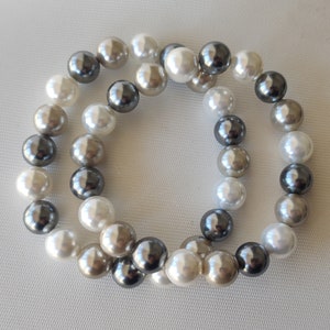 May include: A double strand pearl bracelet with white, grey, and black pearls.