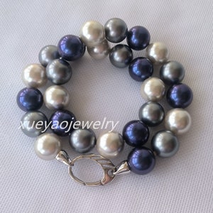 以下が含まれることがあります： シルバーの留め具が付いた真珠のネックレス。ネックレスは白、グレー、濃い青の3色の真珠で作られています。