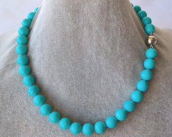 May include: A single-strand necklace composed of uniform, smooth, round turquoise-coloured beads. The necklace features a polished silver-toned metal barrel clasp mechanism that connects the two ends of the beaded strand securely together.