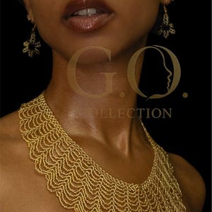 May include: A gold beaded necklace with a scalloped design. The necklace is worn with matching earrings. The image also displays the text "G.O. COLLECTION" in gold.