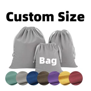 May include: Three gray drawstring bags of varying sizes, with the word "Bag" printed on the smallest bag. The text "Custom Size" is above the bags. Below are color swatches in shades of green, gray, blue, brown, purple, yellow, and red.