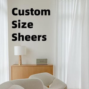 May include: White sheer curtains hanging in front of a window. The text "Custom Size Sheers" is displayed on the wall. A wooden cabinet with a lamp and a speaker are in the foreground. Two white chairs are in the foreground.