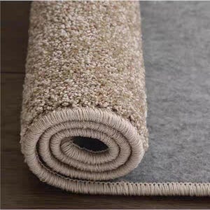 Puede incluir: Alfombra beige enrollada con una superficie texturizada, que revela un reverso gris. El borde de la alfombra est&aacute; cuidadosamente terminado con un borde beige a juego. La imagen resalta la textura y el color afelpado de la alfombra.