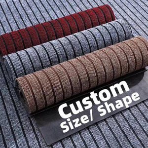 Puede incluir: Felpudos enrollados en rojo, gris y marr&oacute;n con patrones de rayas verticales. Las alfombras se muestran sobre una superficie gris a rayas. El texto "Custom Size/ Shape" es visible en una etiqueta negra.