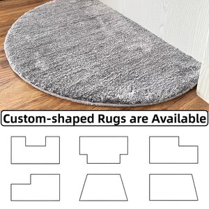 Puede incluir: Una alfombra gris semicircular con superficie texturizada sobre un suelo de madera. La alfombra est&aacute; cerca de una puerta blanca. El texto en la parte inferior dice "Custom-shaped Rugs are Available" con opciones de forma.