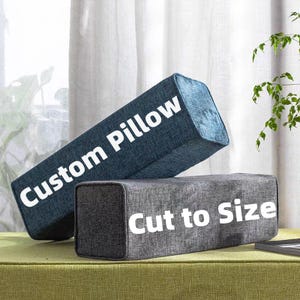 May include: Two rectangular pillows. One is dark blue with the text "Custom Pillow" in white. The other is gray with the text "Cut to Size" in white. Both pillows have a textured fabric.