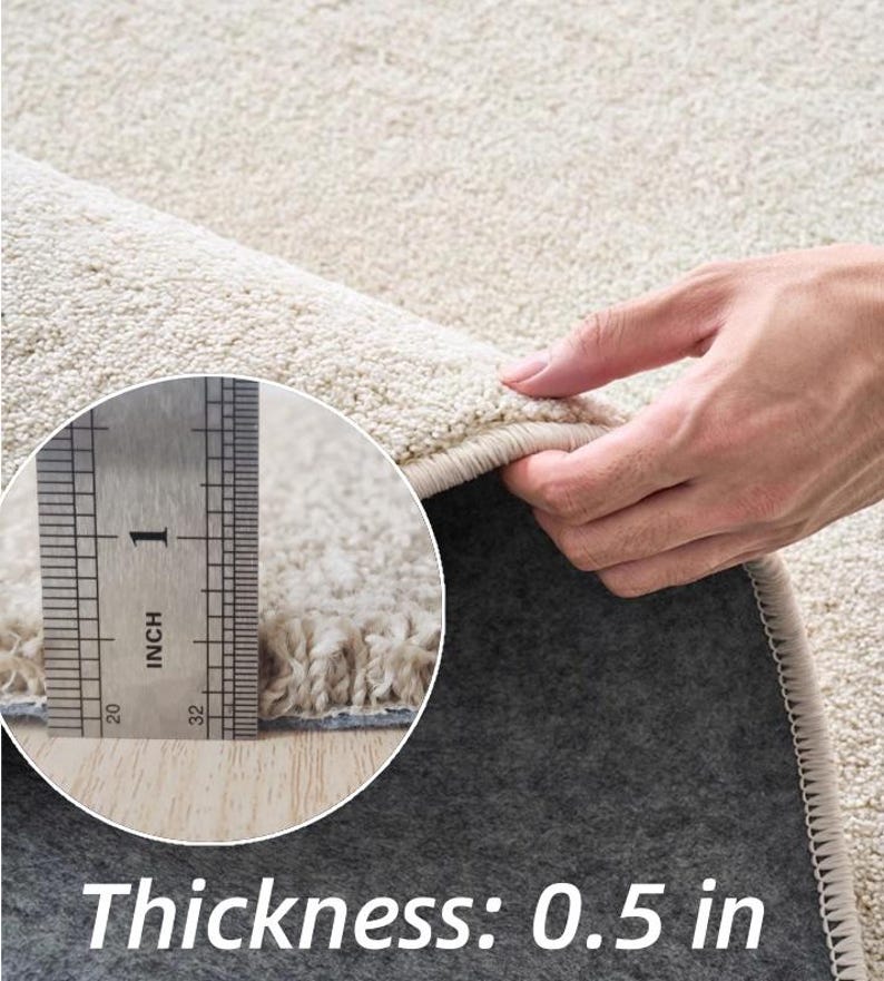 Puede incluir: Primer plano de una alfombra beige con un pelo grueso y texturizado. El grosor de la alfombra es de 1,27 cm. La alfombra tiene un reverso gris oscuro y un borde beige claro. El texto "Thickness: 0.5 in" se muestra en la parte inferior.