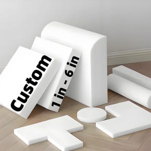 May include: Various white foam shapes, including rectangular, cylindrical, and L-shaped pieces. The text "Custom" is printed on one piece, and "1 in - 6 in" is printed on another. The shapes are arranged on a light-coloured wooden surface.