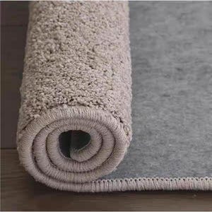 Puede incluir: Alfombra de ba&ntilde;o gris claro enrollada, con una superficie texturizada y afelpada. La secci&oacute;n enrollada revela un patr&oacute;n en espiral, mientras que la parte desenrollada muestra un respaldo liso y gris. La alfombra est&aacute; dise&ntilde;ada para uso en el ba&ntilde;o.