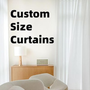 May include: White sheer curtains hang in front of a window, with the text "Custom Size Curtains" on the wall. A wooden cabinet with a lamp and speaker sits below the text. Two cream-colored chairs are in the foreground.