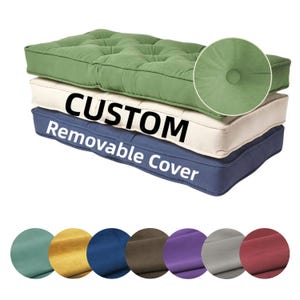 May include: Three custom futon cushions stacked, each in a different color: green, cream, and navy blue. The top cushion is green, with a button-tufted design. The middle cushion is cream, and the bottom cushion is navy blue. The text "CUSTOM Removable Cover" is displayed.