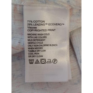 May include: A white fabric care label with black text reading 71% COTTON, 29% LENZING ECOVERO VISCOSE, and COPYRIGHTED PRINT. It includes care instructions for machine washing, non-chlorine bleach, tumble drying, and ironing, plus five laundry symbols.