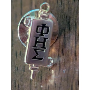 May include: A gold-toned metal lapel pin featuring a rectangular vertical bar with the Greek letters Phi, Eta, and Sigma engraved in black. The pin has a circular backing and a small loop at the top, with a post extending from the bottom edge.