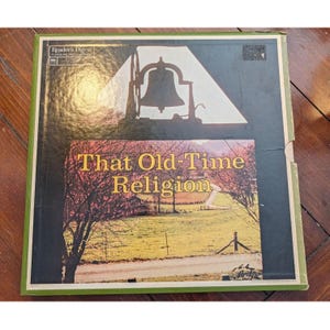 May include: A square vinyl record box set titled That Old-Time Religion by Reader's Digest. The cover features a black silhouette of a church bell at the top and a photograph of a rural landscape with trees and a dirt road in the center.