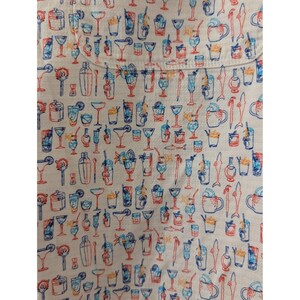 May include: A white fabric featuring a repeating pattern of various cocktail glasses, shakers, and stirrers in shades of blue, orange, and red. The design includes diverse glassware shapes such as coupes, highballs, and mugs, all rendered in line art.