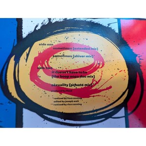 Puede incluir: Un disco de vinilo con un dise&ntilde;o colorido. La obra de arte presenta un c&iacute;rculo amarillo con un remolino rojo y el texto "side one" y "side two". El disco enumera t&iacute;tulos de canciones como "sometimes" y "sexuality".