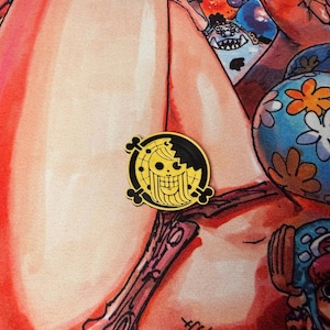 May include: A round, black and yellow enamel pin featuring a skull and crossbones design. The pin has a gold skull with a partial black outline and is surrounded by a black border. The pin is a collectible item.