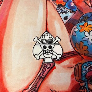 May include: A white and black Ace of Spades pin featuring a skull with crossbones, goggles, and flames. The pin is set against a colorful background with cartoon illustrations.