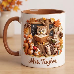 Op de afbeelding: Een witte keramische mok met een bruin handvat en binnenkant, voorzien van een reliëfillustratie van een uil die voorleest aan een vos, eekhoorn, konijn en egel in een bos met een schoolbord en de tekst Mrs. Taylor onderaan gedrukt.