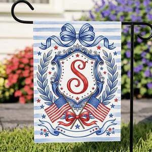 May include: A patriotic garden flag featuring a blue and white striped background. The flag displays a red letter "S" within a blue and white crest, surrounded by stars, laurel leaves, and two American flags. A blue bow and ribbon complete the design.