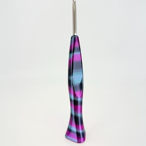 May include: A crochet hook with a silver metal hook and a handle with a plaid pattern in shades of purple, black, and teal. The handle has a flared, ergonomic design for comfortable use. This craft tool is ideal for crocheting projects.