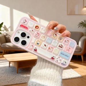 Puede incluir: Funda de teléfono rosa con diseño de teclado con personajes de Hello Kitty. La funda tiene un marco rosa claro y una base blanca con botones cuadrados de colores. Las palabras "Hello Kitty" están impresas en un botón azul.