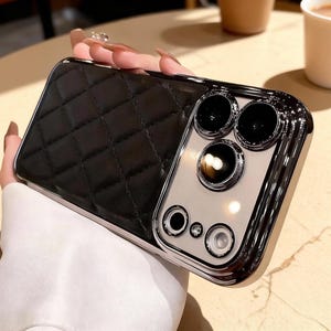 May include: Black quilted phone case with a silver metallic frame. The case features a diamond pattern on the back and a shiny silver camera module with multiple lenses.