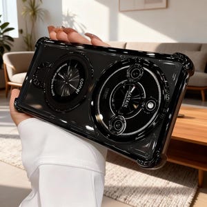 May include: Black phone case with a unique design featuring two circular elements with text. The case has a clear border and a glossy finish. One circle says "coinel" and the other says "MATAiX".