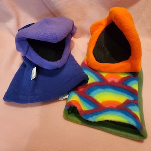 May include: Two hand puppets, one purple with a black mouth and the other orange with a black mouth. The orange puppet has a rainbow patterned body.