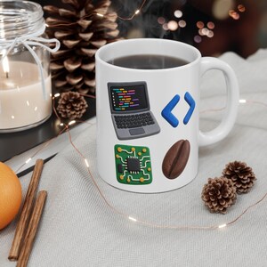 Op de afbeelding: Een witte keramische mok met vier verschillende grafische iconen: een grijze laptop met kleurrijke code, een blauw haakjessymbool, een groene printplaat met een centrale chip en een enkele bruine koffieboon.