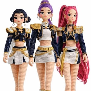 Puede incluir: Tres muñecas de ganchillo hechas a mano con detalles. Cada muñeca tiene un peinado único, incluyendo negro, morado y rosa. Llevan trajes a juego con chaquetas azul marino, faldas blancas y detalles dorados. Las muñecas están de pie una al lado de la otra.