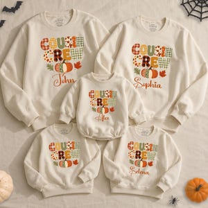 May include: A set of five cream-colored crewneck sweatshirts featuring a graphic print with the text COUSIN CREW, autumn-themed plaid patterns, and pumpkin illustrations. Some sweatshirts include personalized names such as John, Sophia, Alex, and Selena printed in a cursive script below the graphic.