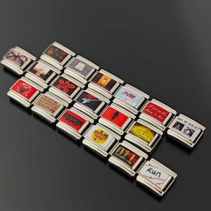 May include: A collection of silver-toned charm bracelets with various colorful designs. The charms feature images and text, including "Stranger Things," "Friends don't lie," and "Run."
