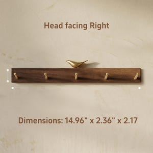 May include: A wooden wall-mounted coat rack with six brass hooks and a decorative brass bird. The rack is 14.96 inches long, 2.36 inches wide, and 2.17 inches high. The text "Head facing Right" and "Dimensions: 14.96" x 2.36" x 2.17" are visible.