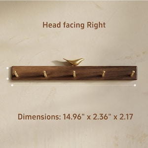 May include: A wooden wall-mounted coat rack with five brass hooks and a decorative gold-colored bird. The rack measures 14.96 inches long, 2.36 inches wide, and 2.17 inches high. The text "Head facing Right" is above the rack.
