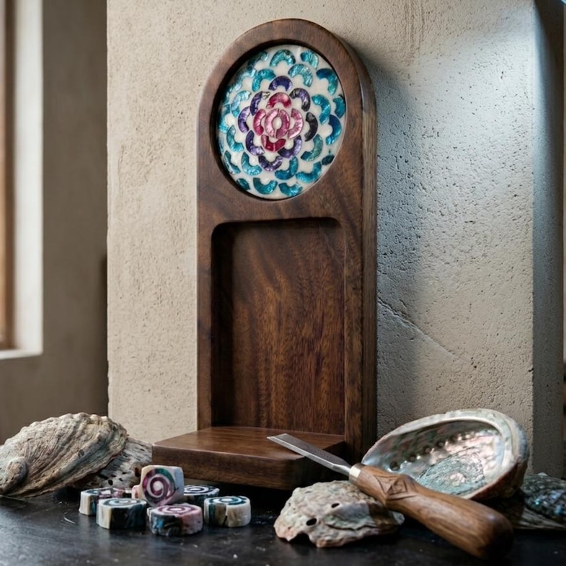 May include: A wooden display stand with a decorative, colorful floral design. The stand has a carved-out section and a small shelf. A carving tool and several small, decorative soaps are also present.
