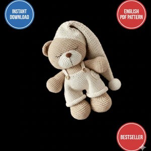 May include: A crocheted teddy bear wearing a cream-coloured nightcap and dungarees. The bear has closed eyes and a brown nose. The image includes the text "INSTANT DOWNLOAD", "ENGLISH PDF PATTERN", and "BESTSELLER".
