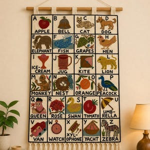 May include: A rectangular wall hanging featuring an embroidered alphabet grid from A to Z. Each letter is paired with a colourful illustration and its corresponding word, such as Apple, Bell, Cat, and Dog. The textile piece has a wooden rod and tassels.