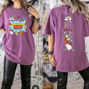 May include: A purple short-sleeve t-shirt featuring a graphic print. The front displays the text "PROVIDER STORY" with medical and western-themed icons. The back features a vertical arrangement of the same icons, including a medical bag and stethoscope.