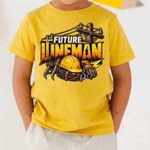 May include: A mustard yellow t-shirt featuring a graphic print of a utility pole, a yellow hard hat, and coiled cables. The text "FUTURE LINEMAN" is printed in bold, block letters above the illustration, which includes a lightning bolt icon.