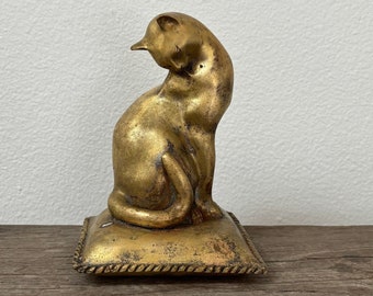 Vintage brass like cat or kitten statue figurine, made of alloy metal, on pillow cushion