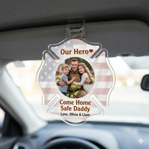 Puede incluir: Accesorio transparente para coche con una foto de un bombero y dos niños, sobre un fondo de la bandera estadounidense. El texto dice "Our Hero" y "Come Home Safe Daddy." Incluye los nombres Olivia y Liam.
